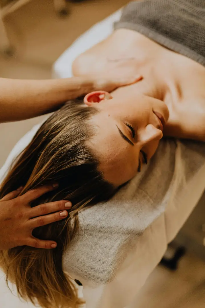 photo of woman recieving a neck massage lyign down on a massage table